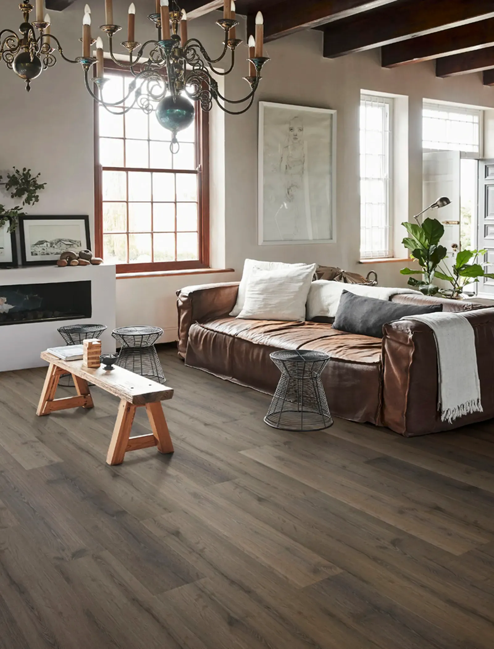 Phòng khách ấm cúng với sàn gỗ tối màu, sofa da và trang trí mộc mạc.